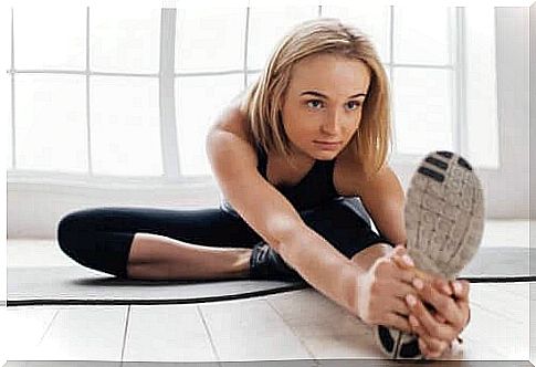 Girl in black doing leg stretches.